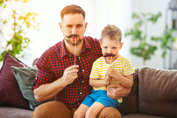 Vater und Sohn posieren mit Schnurrbart-Accessoires.