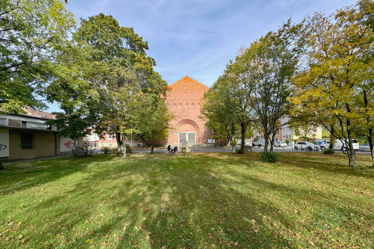 Ismail-Yasar-Platz mit Kirchenportal und Grünanlage