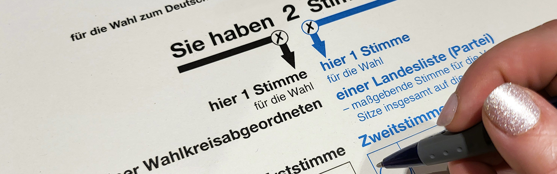 Eine Hand mit einem Stift über einem Stimmzettel in Nahaufnahme