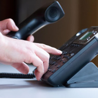 Rechte Hand wählt auf der Telefon-Tastatur, linke hält den Hörer.