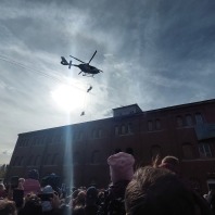 Polizeishow beim Tag der offenen Tür. Ein Hubschrauber seilt zwei SEK-Beamte ab. Im Vordergrund viele Besucher. 