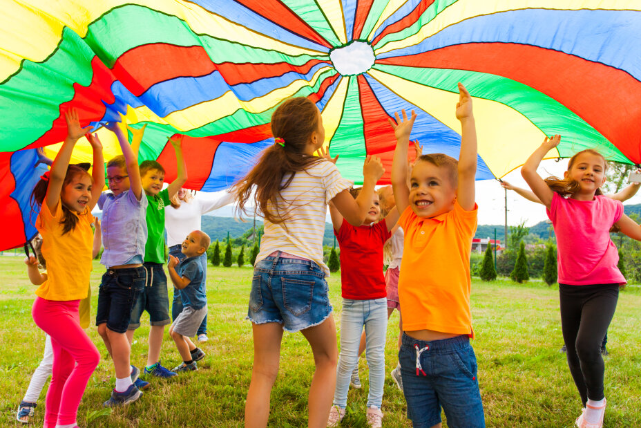 Happy laughing boy standing hands-up under colorful cloth. Children having fun on the birthday party, Bild © AdobeStock